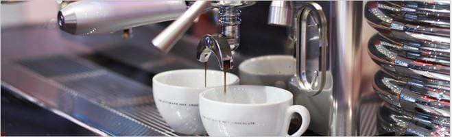 weaverscoffee.mom Two white coffee cups at an espresso machine filled with Espresso Coffee.